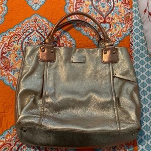 Kate Spade New York gold and copper handbag with zipper pockets on the side.